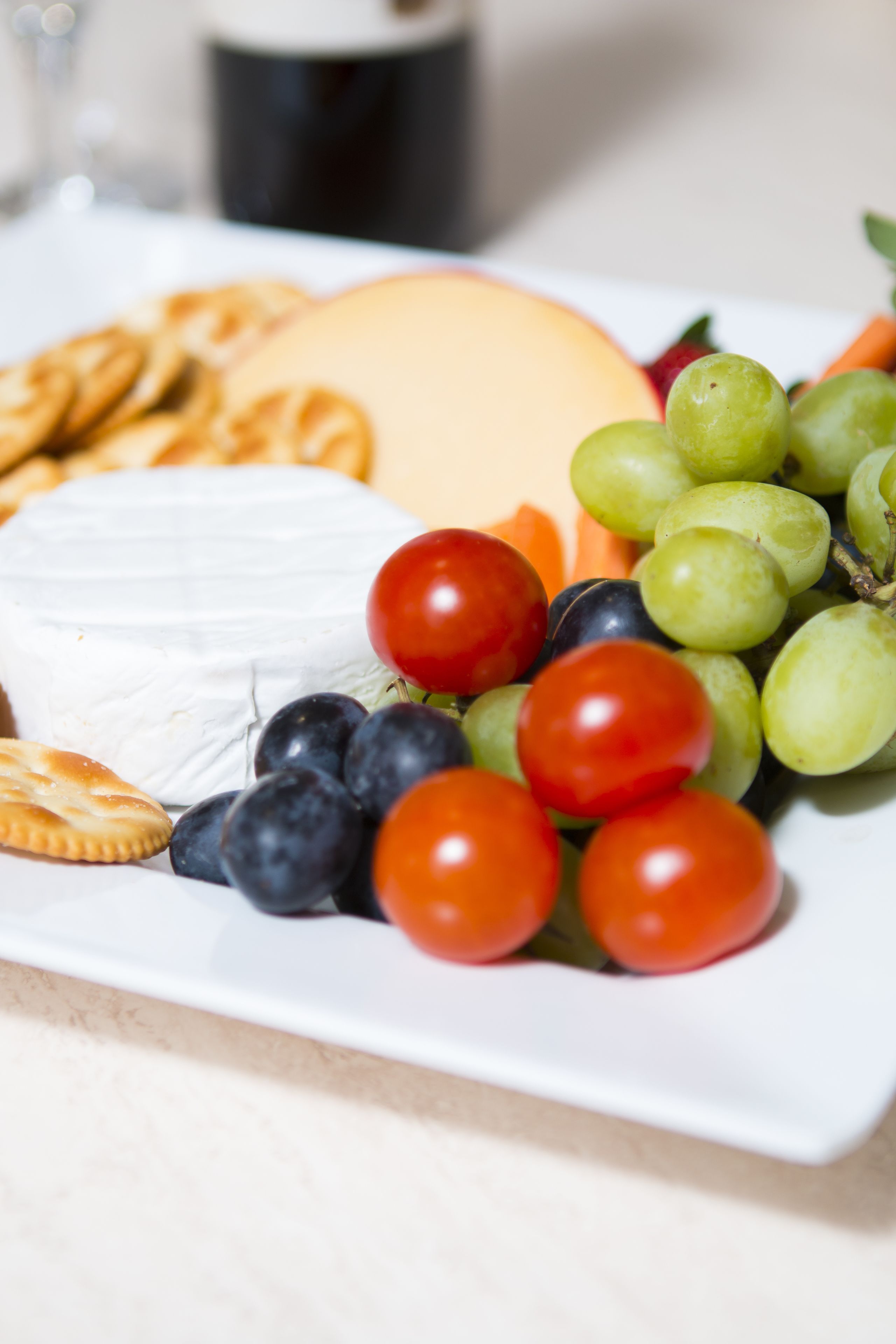 Une assiette garnie d’un assortiment de fromages, de raisins et de crackers.