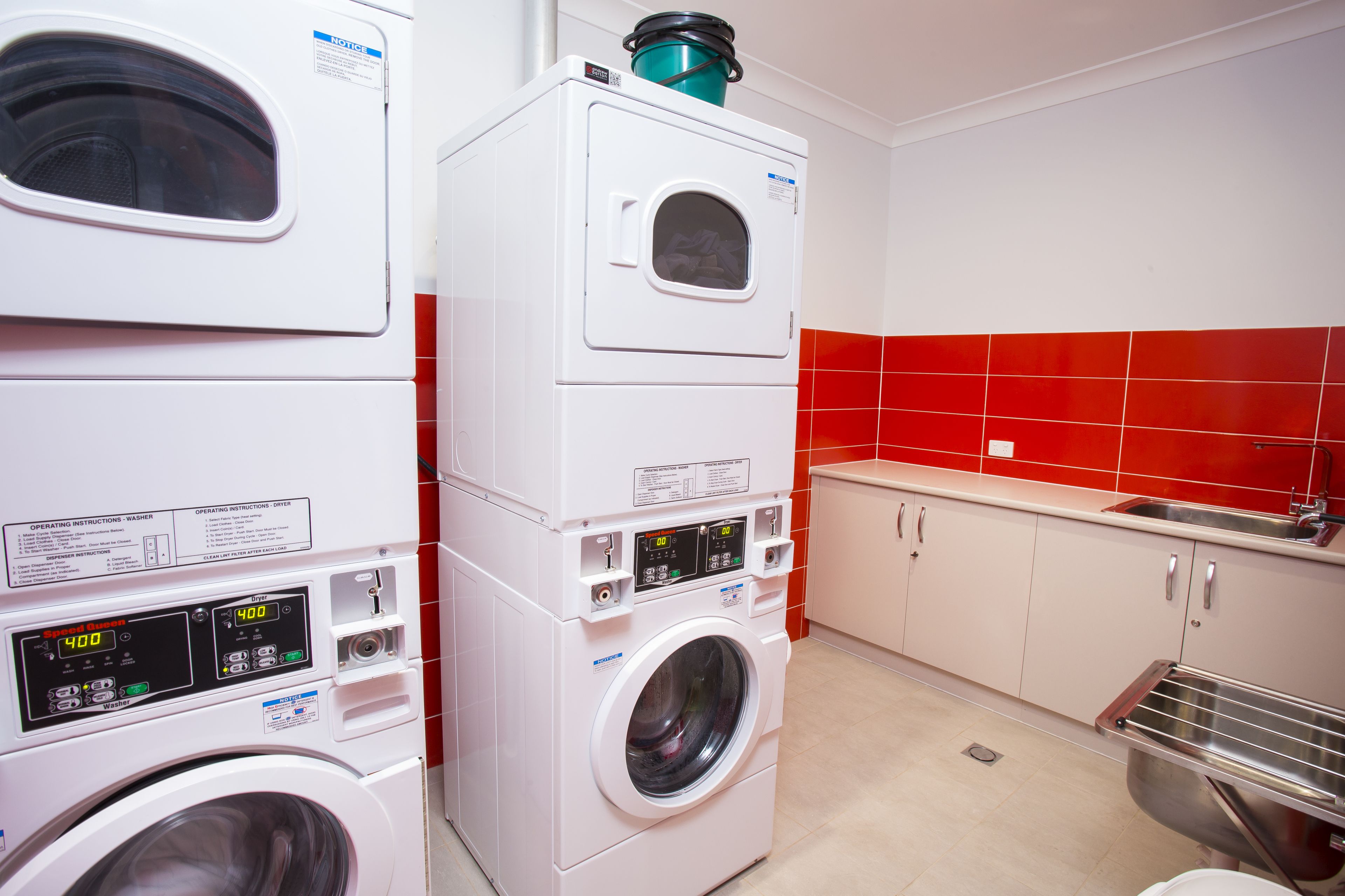 A laundry area with stacked washing machines and a sink.