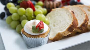 A plate with a cupcake, grapes, strawberries, and slices of bread.