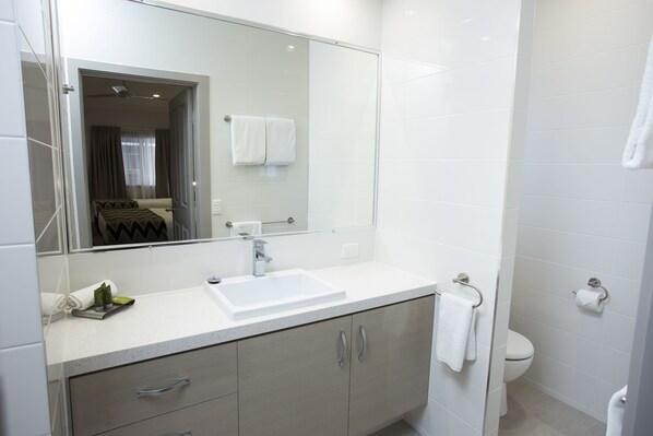 Une salle de bain moderne avec un lavabo blanc, un miroir et des toilettes.