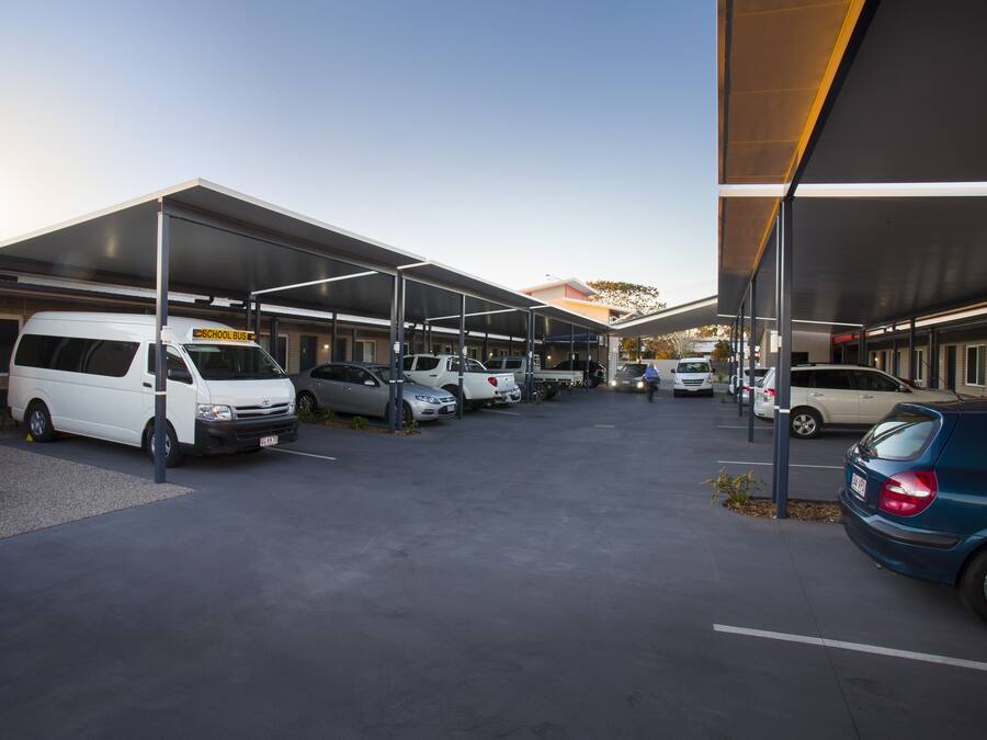 A parking area with multiple vehicles, including a school bus, and covered structures.