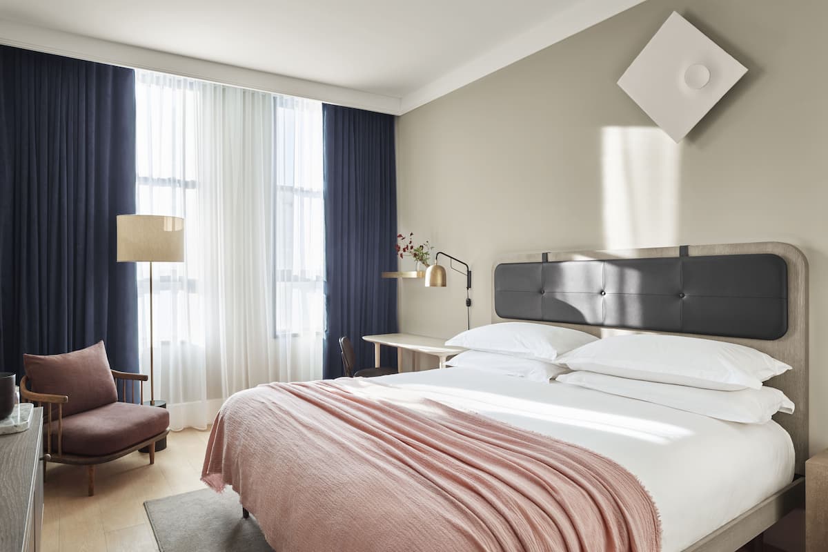 Een hotelkamer met een bed, een stoel, een bureau en een lamp.