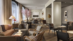 A modern living room with a sofa, armchairs, a dining area, and a TV. - 11 Howard, New York, a Member of Design Hotels (New York)