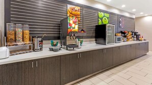 Un área de cocina moderna con estación de autoservicio que ofrece cereales, gofres y una gofrera.