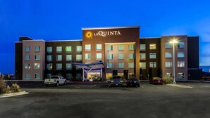 Hotel La Quinta con diseño moderno, destacando una entrada principal y varios espacios de estacionamiento.