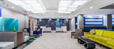 En moderne lobby med reception, siddeområde og et stort vægmaleri.