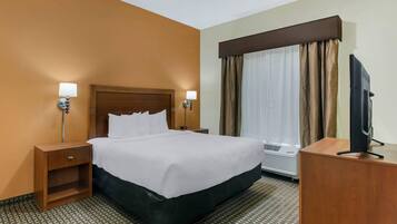 Een hotelkamer met een groot bed, twee nachtkastjes met lampen, een flatscreen televisie op een houten standaard en een airconditioning.