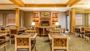 A hotel lobby with multiple seating areas, a fireplace, and a patterned carpet. - MainStay Suites Stanley (Stanley)