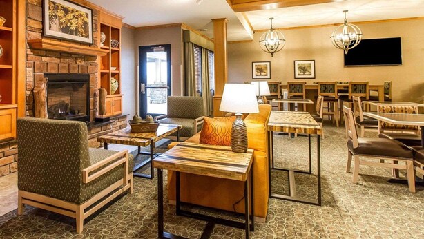 A spacious living area with a fireplace, comfortable seating, and a dining area with tables and chairs. - MainStay Suites Stanley (Stanley)