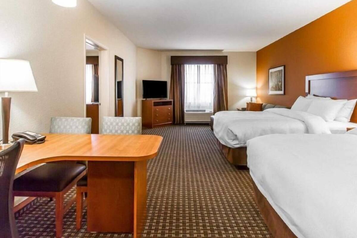 A hotel room with a bed, a desk, a chair, a TV, and a window with curtains.