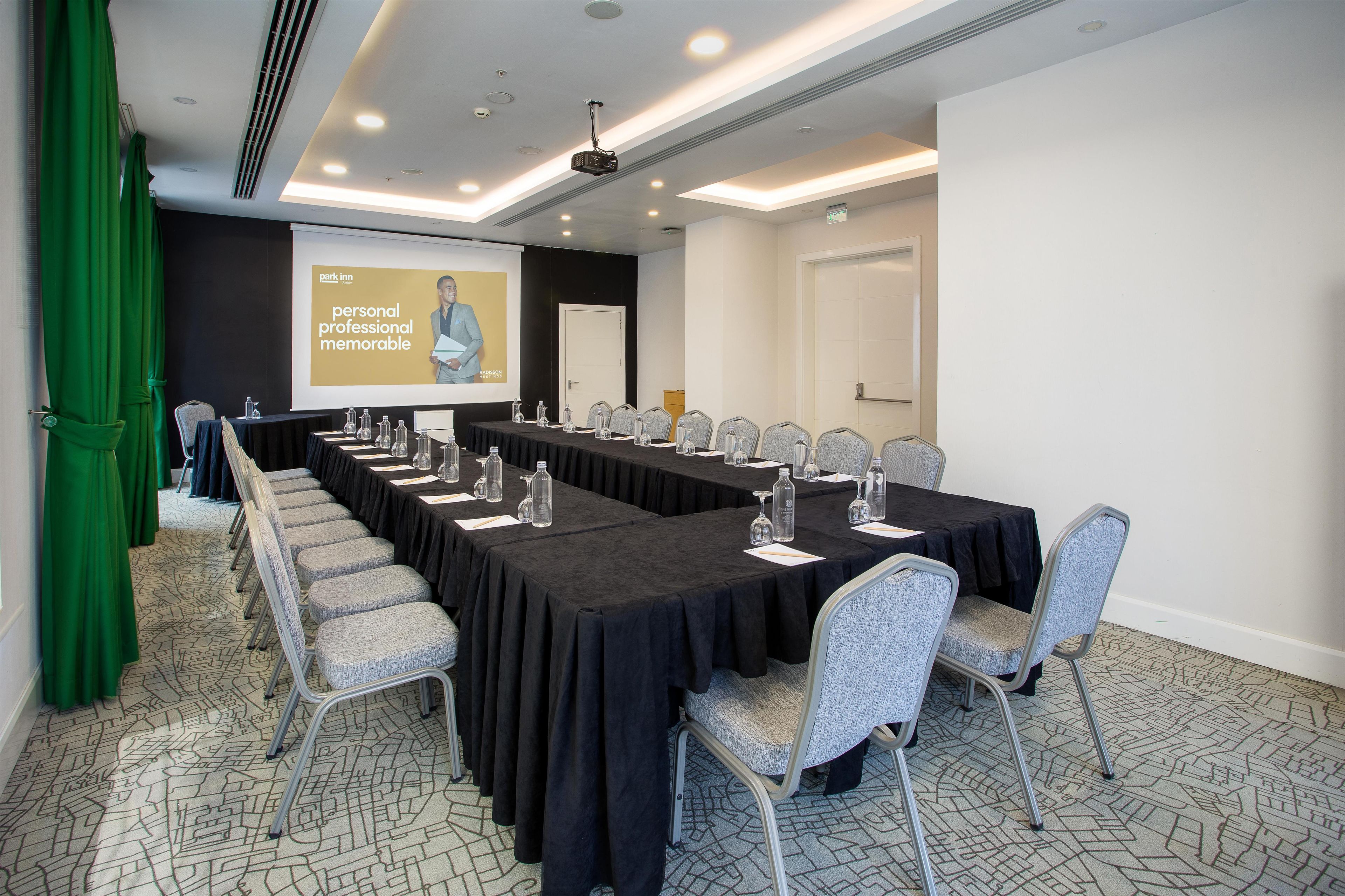 Un salón de conferencias con una mesa larga, sillas, una pantalla de proyector y una presentación sobre experiencias personales, profesionales e inolvidables.
