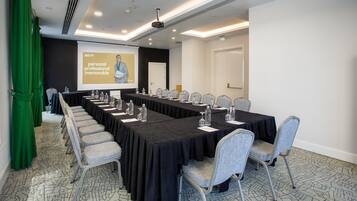 Un salón de conferencias con una mesa larga, sillas, una pantalla de proyector y una presentación sobre experiencias personales, profesionales e inolvidables.
