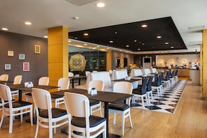 A restaurant with multiple tables and chairs, a checkered floor, and a modern interior design. - Park Inn by Radisson Ankara Cankaya (Ankara)