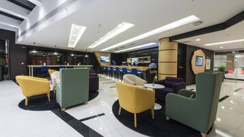 A modern lobby with seating areas, a reception desk, and a bar.