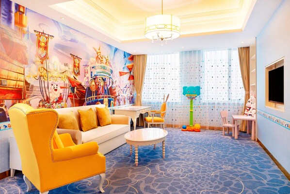 Un salón luminoso y de colores vivos con un sofá amarillo, una mesa blanca y un mural colorido en la pared.