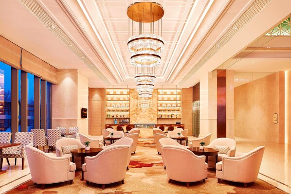 A spacious lobby with a central chandelier, seating area, and a bar with shelves of bottles. - Sheraton Harbin Xiangfang Hotel (Harbin)