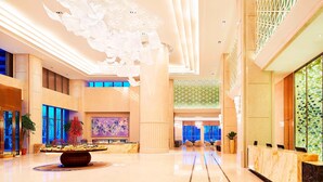 A spacious lobby with a marble reception desk, a large decorative ceiling, and a view of the outdoors through large windows. - Sheraton Harbin Xiangfang Hotel (Harbin)