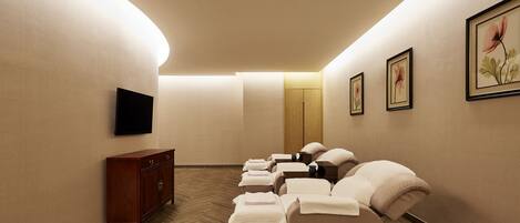 A spa room with massage chairs, a wooden cabinet, and framed artwork on the walls.