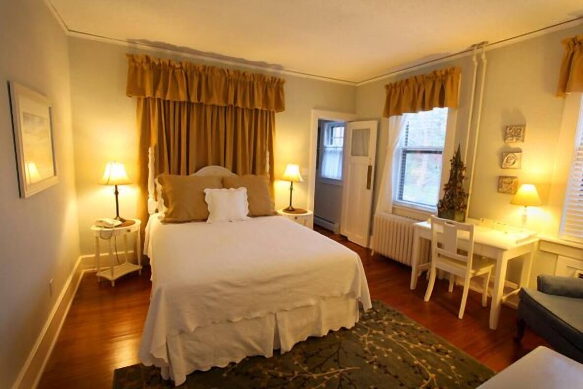 Une chambre à coucher avec un lit, des tables de chevet, un bureau et une chaise.