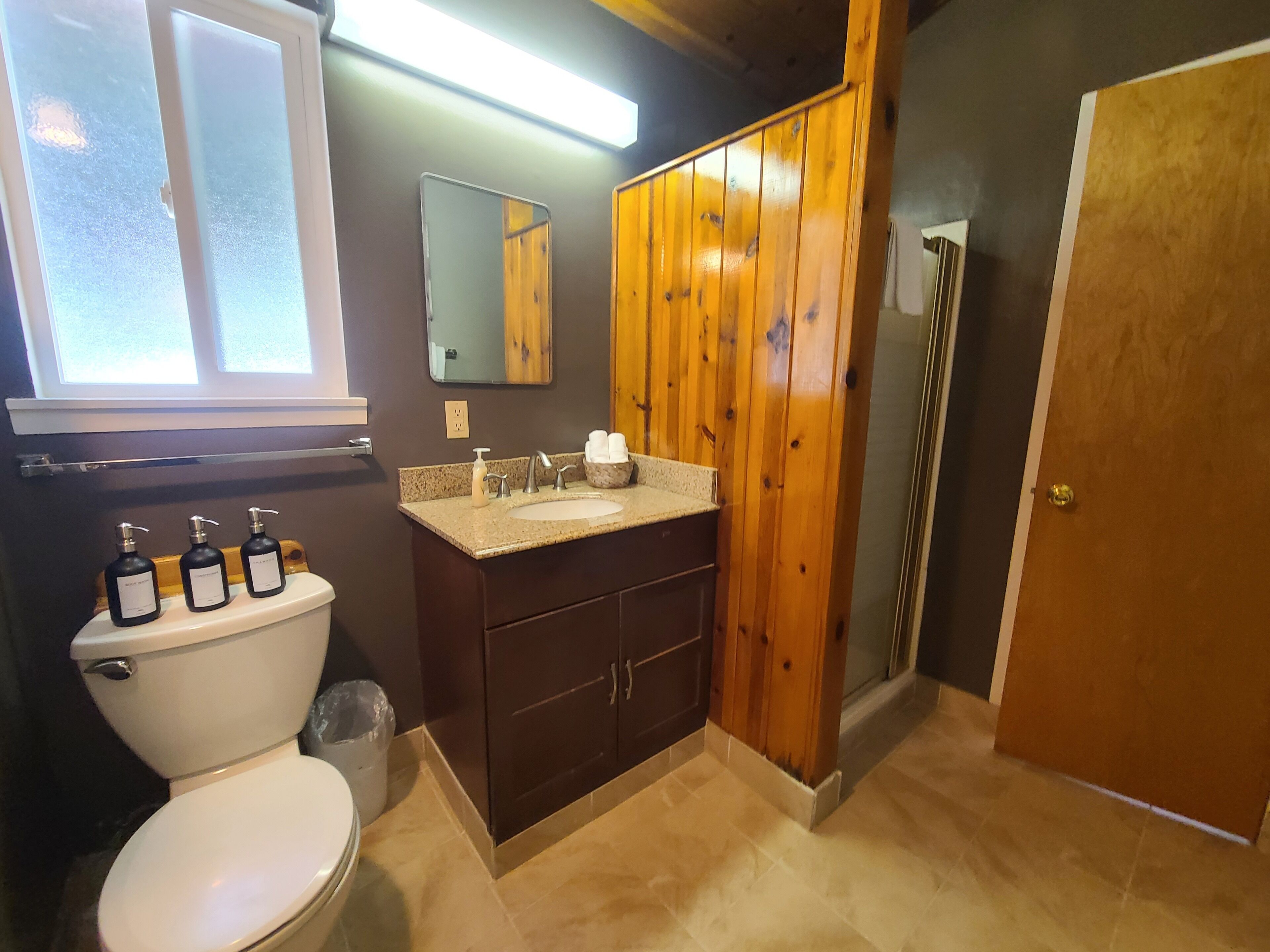 Ein Badezimmer mit Toilette, Waschbecken, Spiegel und Holzschränken.
