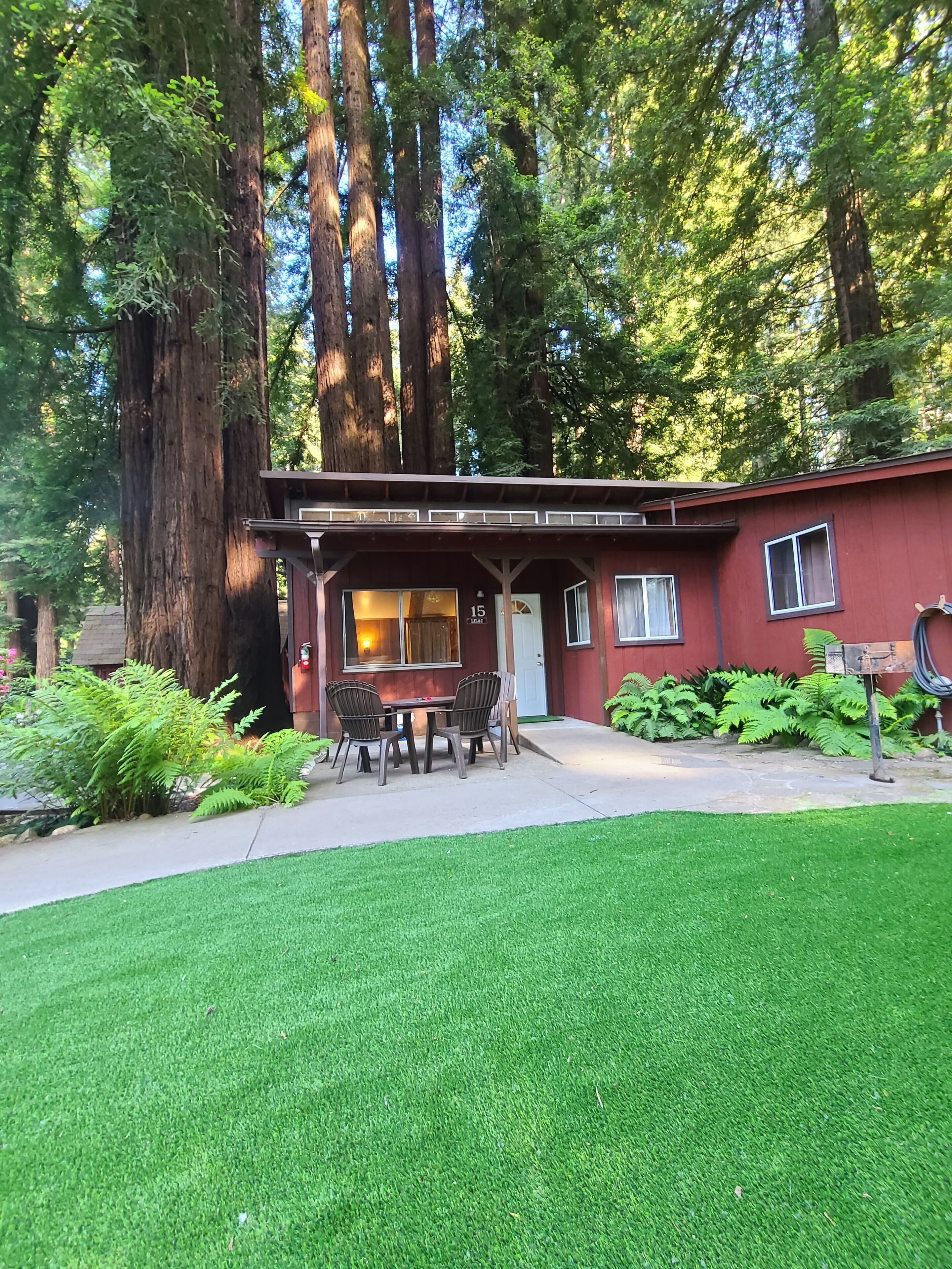 A red building with a covered patio, a dining table, and chairs.