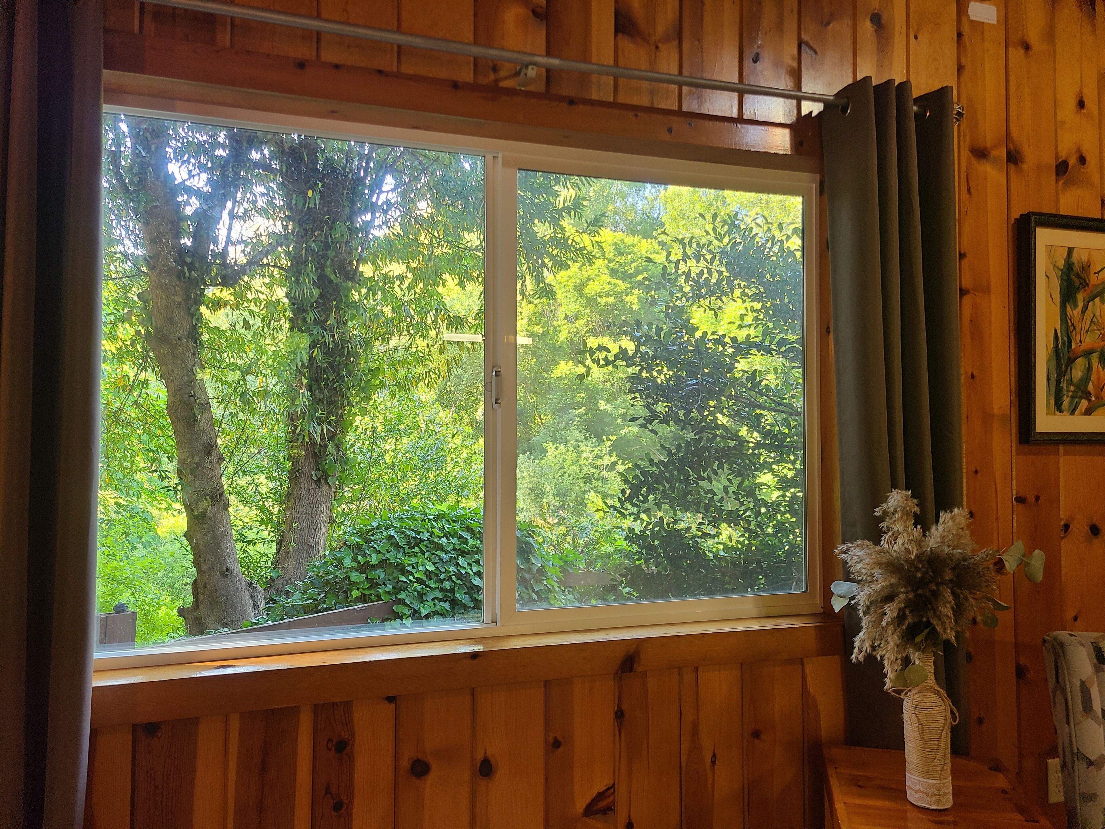 A room with a large window offering a view of trees and greenery outside.