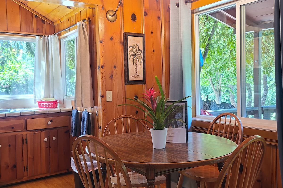 A wooden dining area with a table, chairs, and a hanging light fixture.