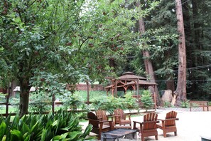 A gazebo, wooden chairs, and a tree with apples in a forested area. - Fern River Resort (Felton)