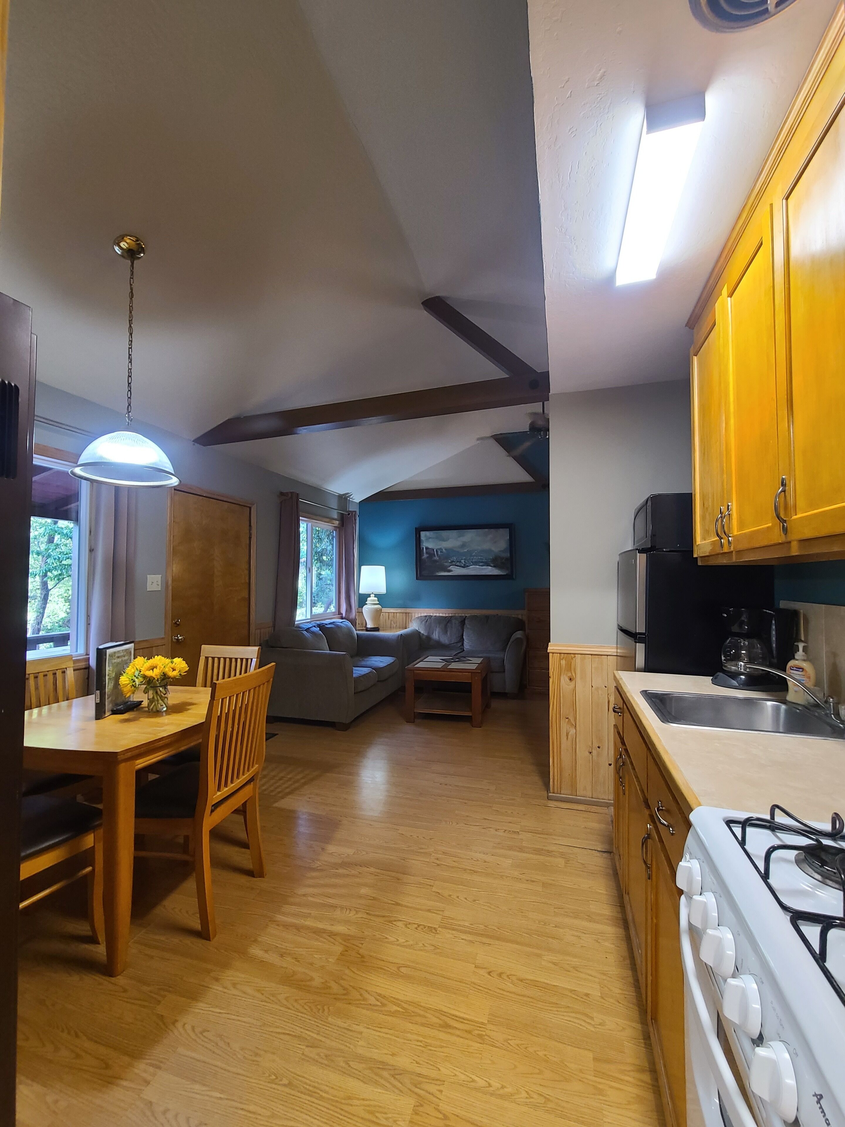 Une cuisine moderne avec des meubles en bois, une cuisinière à gaz et un coin repas comprenant une table et des chaises.