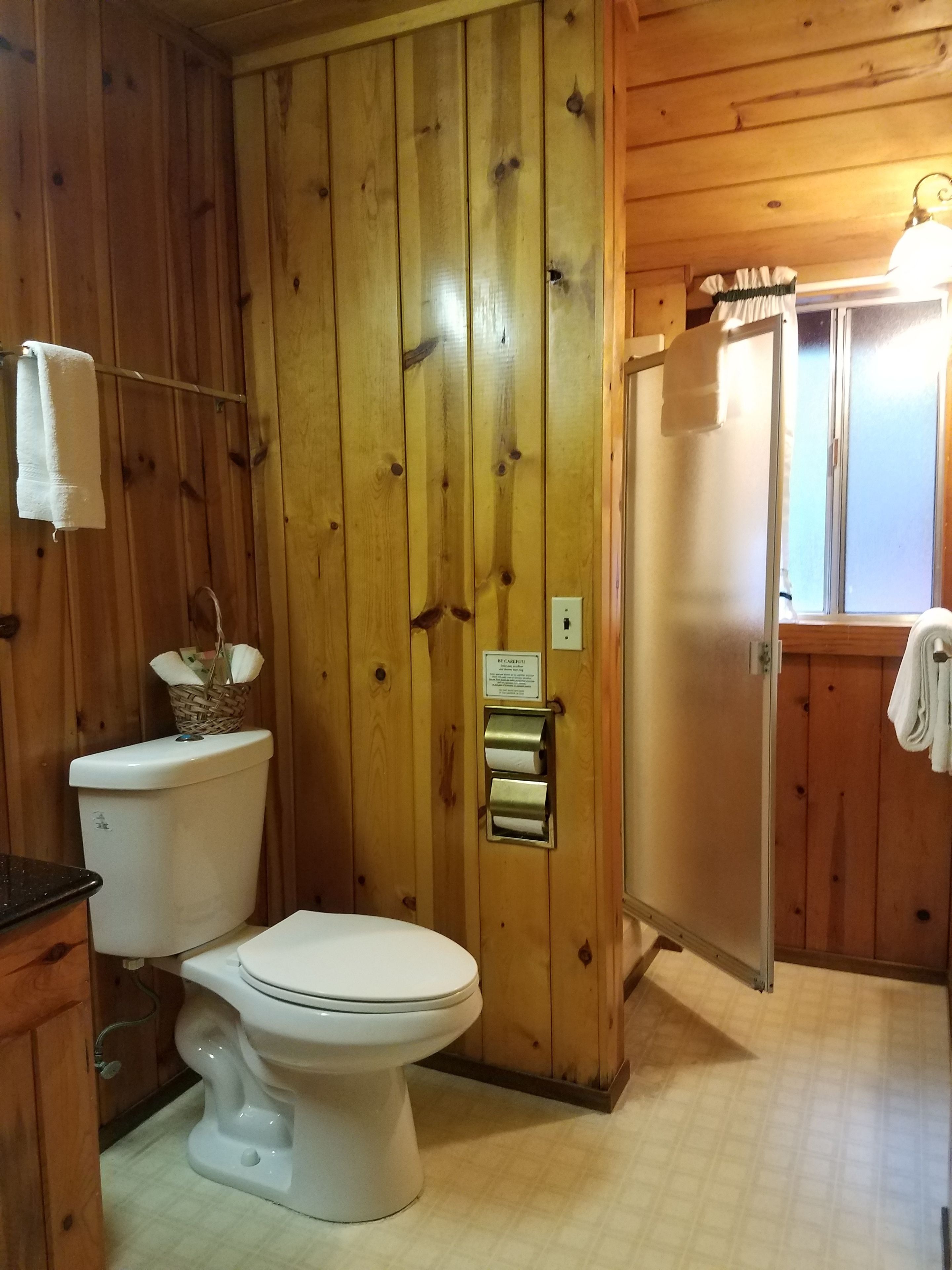Un baño de madera con inodoro, secador de manos y barra para toallas.