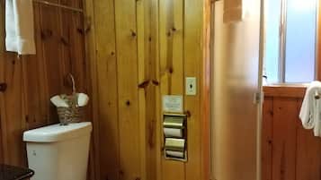 Un baño de madera con inodoro, secador de manos y barra para toallas.