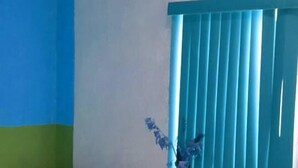 Een kamer met twee bedden, een raam met blauwe luxaflex en een airconditioning aan de muur.