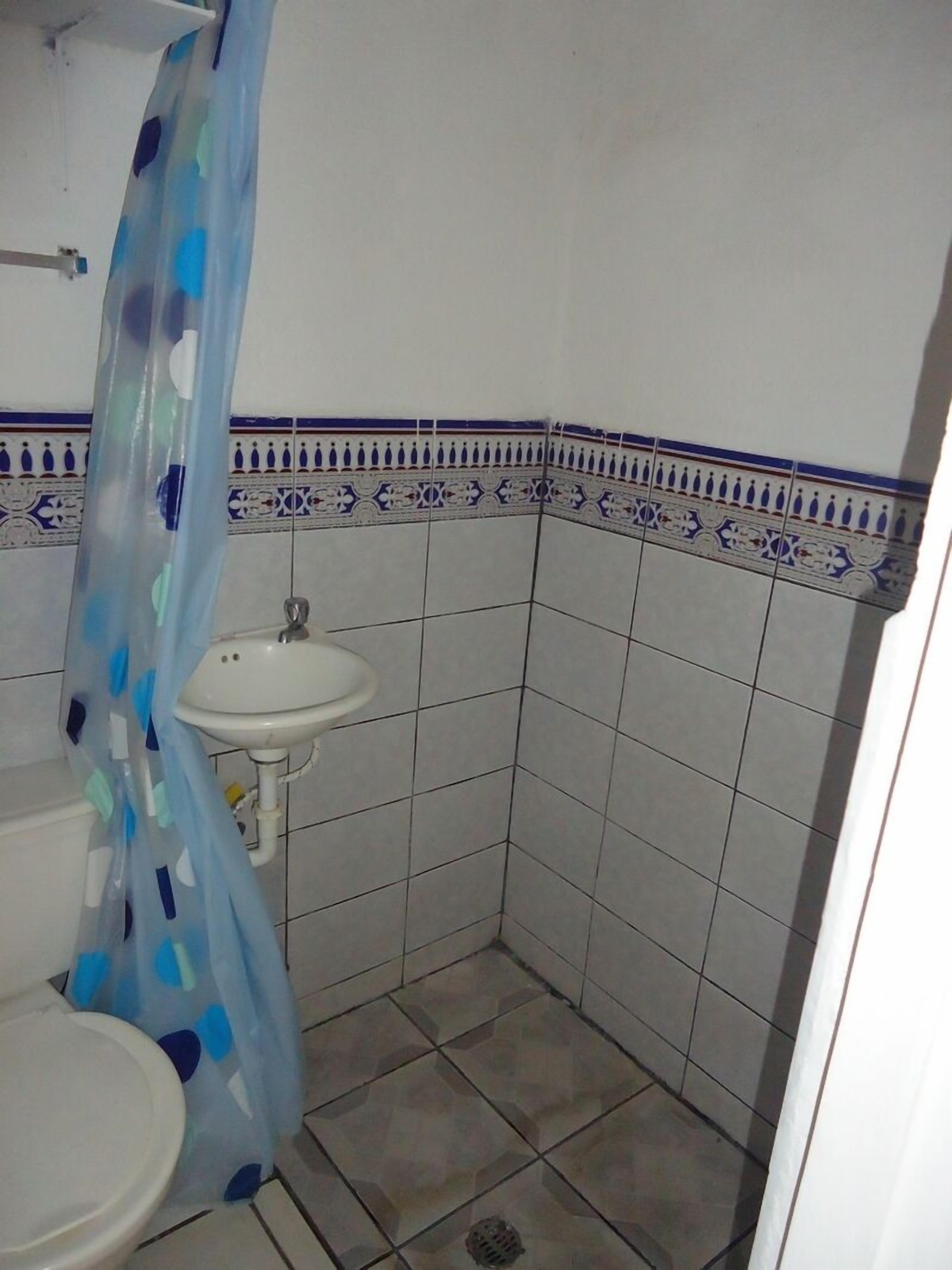 Un bany petit amb un lavabo blanc, un vàter i una cortina de banyera.