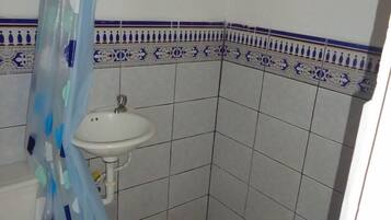 Un bany petit amb un lavabo blanc, un vàter i una cortina de banyera.
