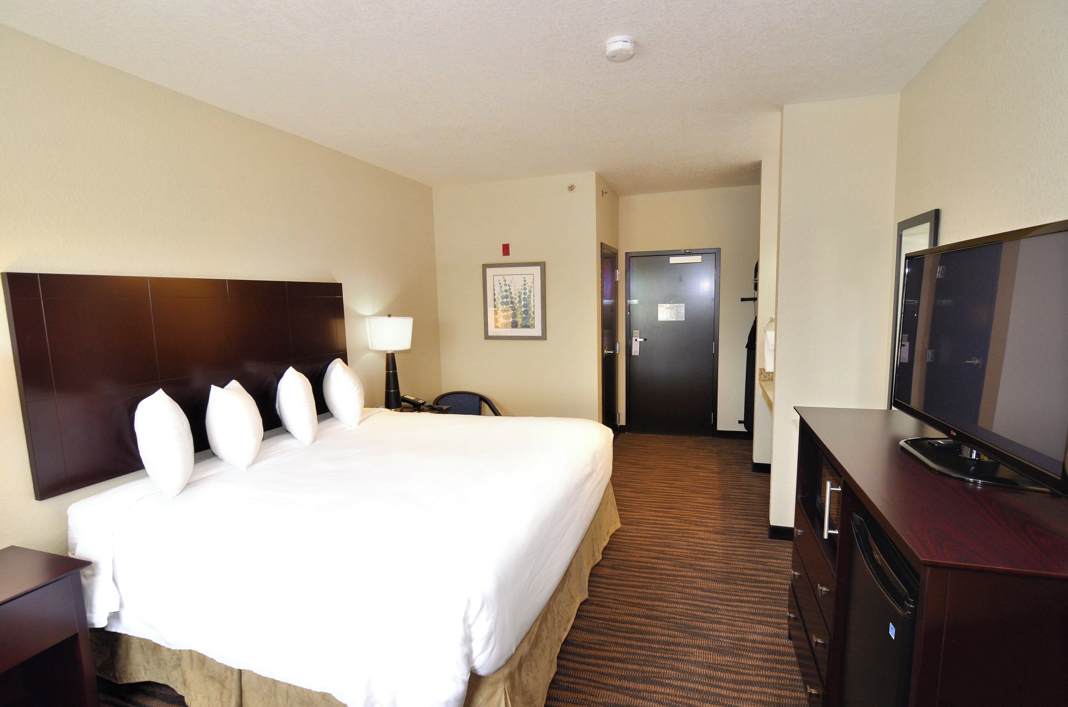 A hotel room with a large bed, a television, a desk, and a chair.