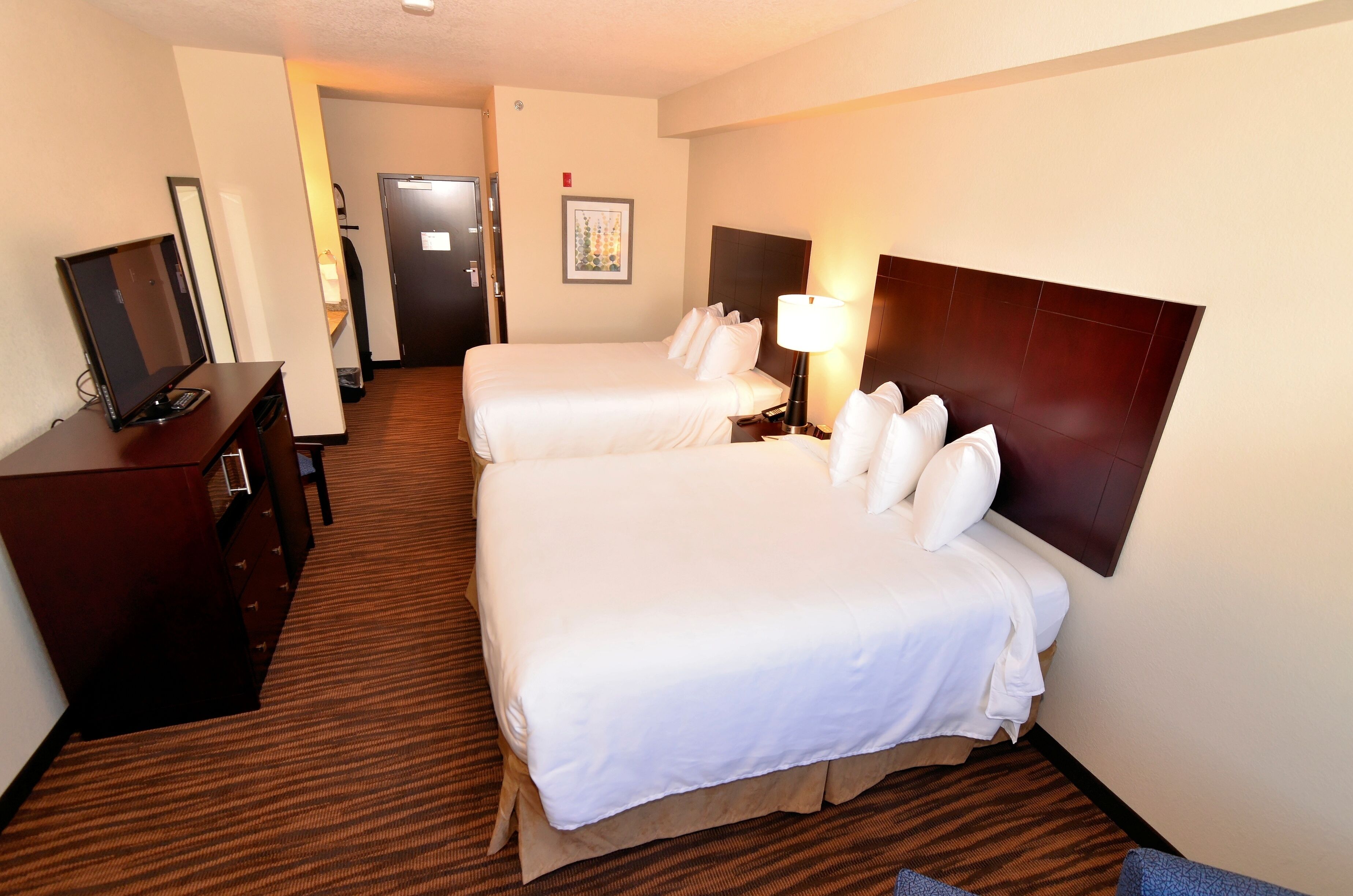 A hotel room with two beds, a desk with a computer, and a TV.