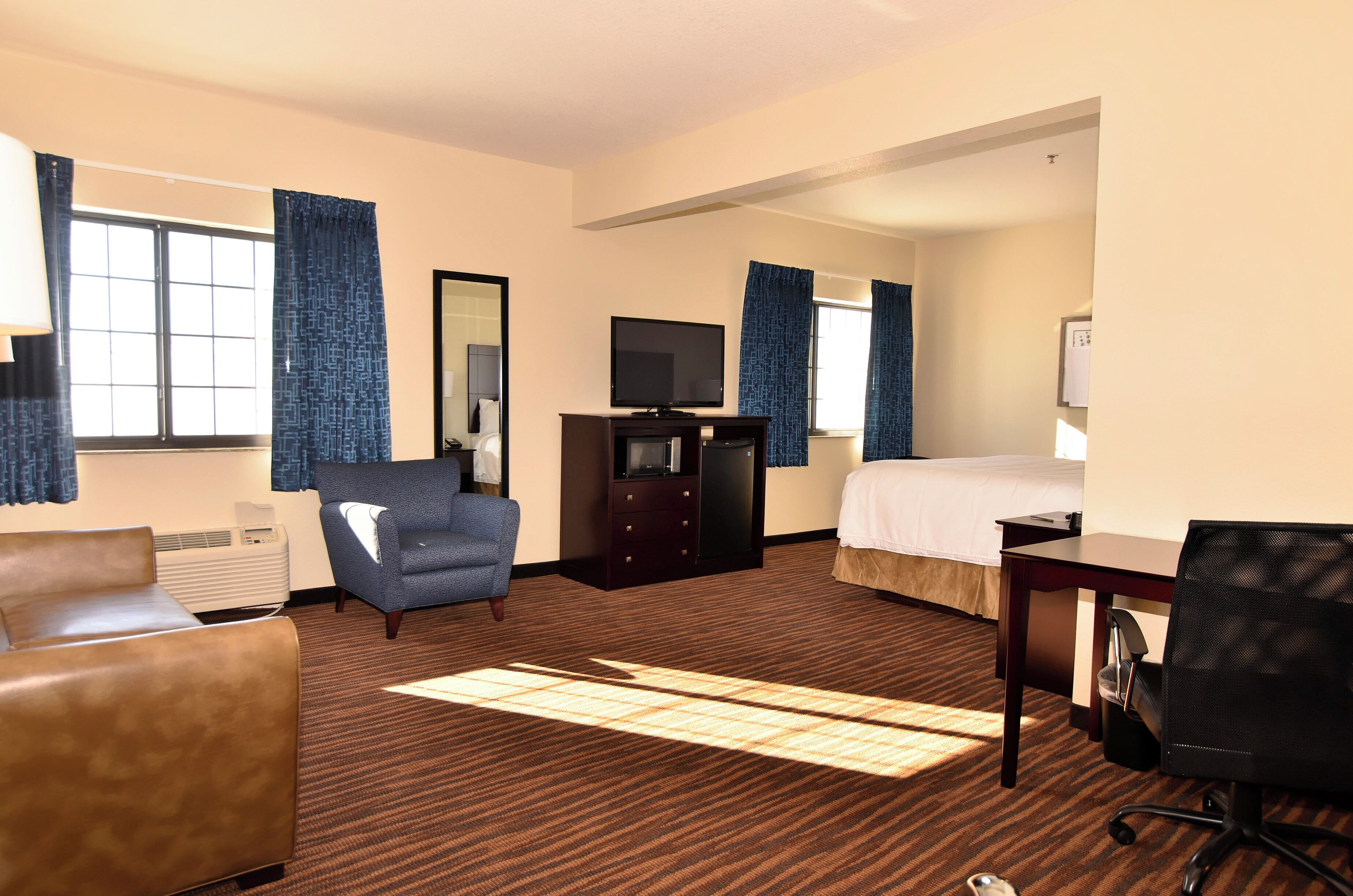Une chambre d’hôtel comprenant un lit, un bureau, une chaise, une télévision et une commode.