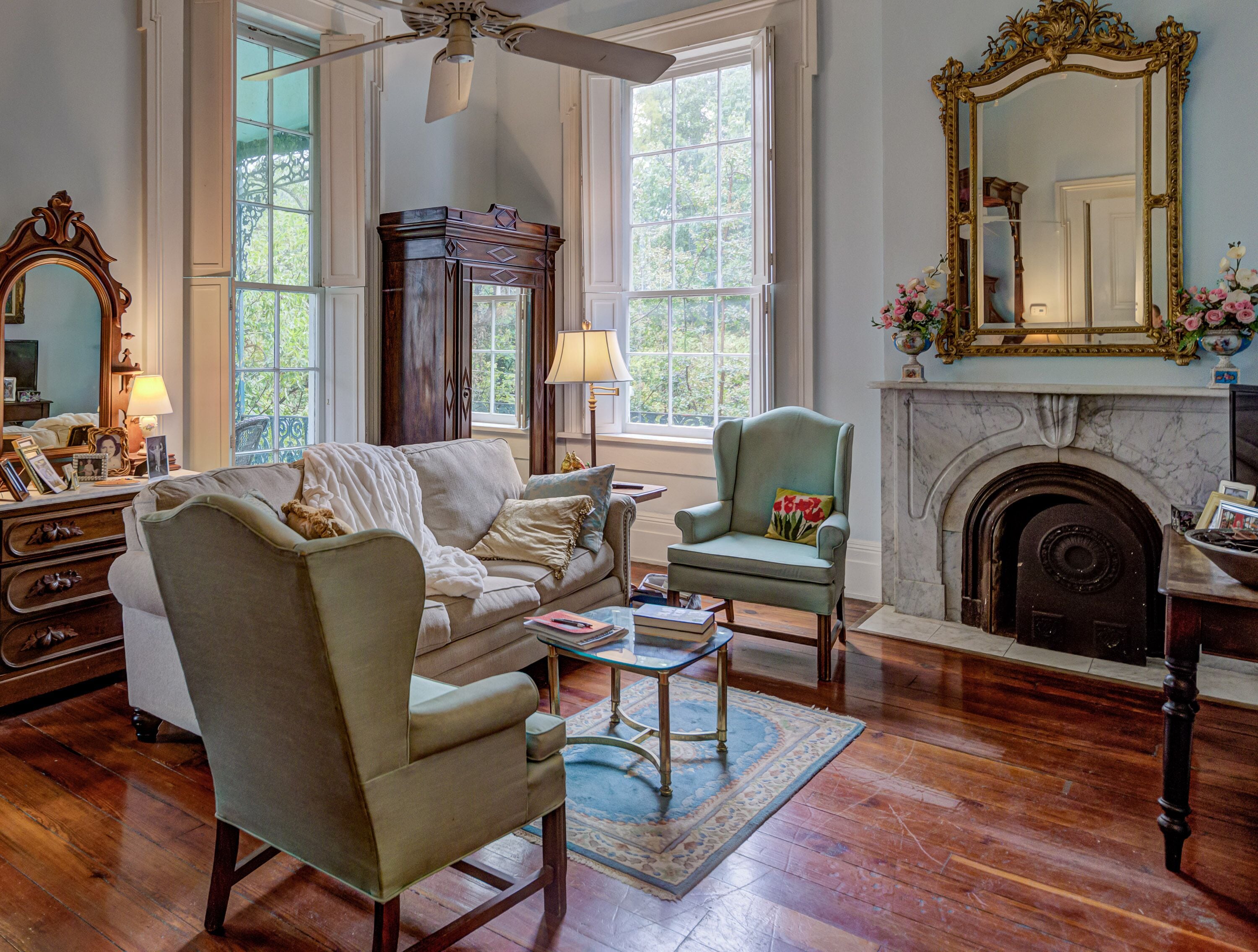 A spacious living room with a large window, a fireplace, and a classic wooden floor.