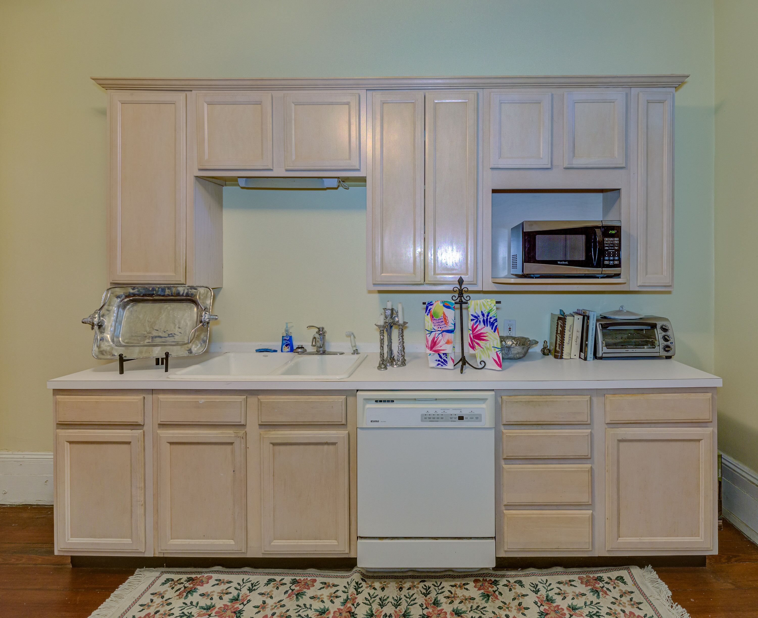 A kitchen with white cabinets, a microwave, a toaster, and a dishwasher.