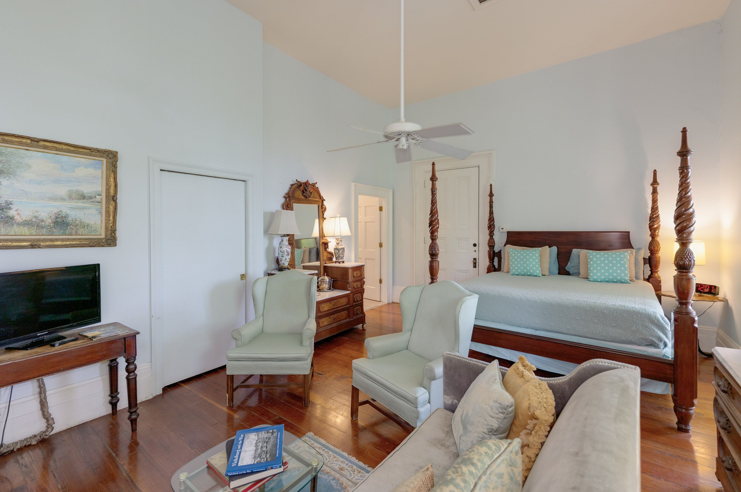 A bedroom with a large bed, a television, a desk, and a chair.