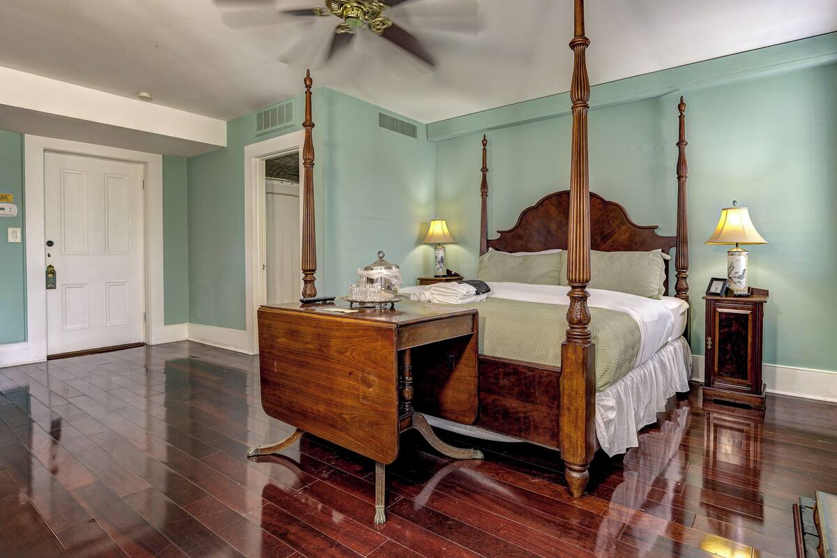 A four-poster bed with a wooden headboard, a nightstand with a lamp, and a bedside table with a lamp.