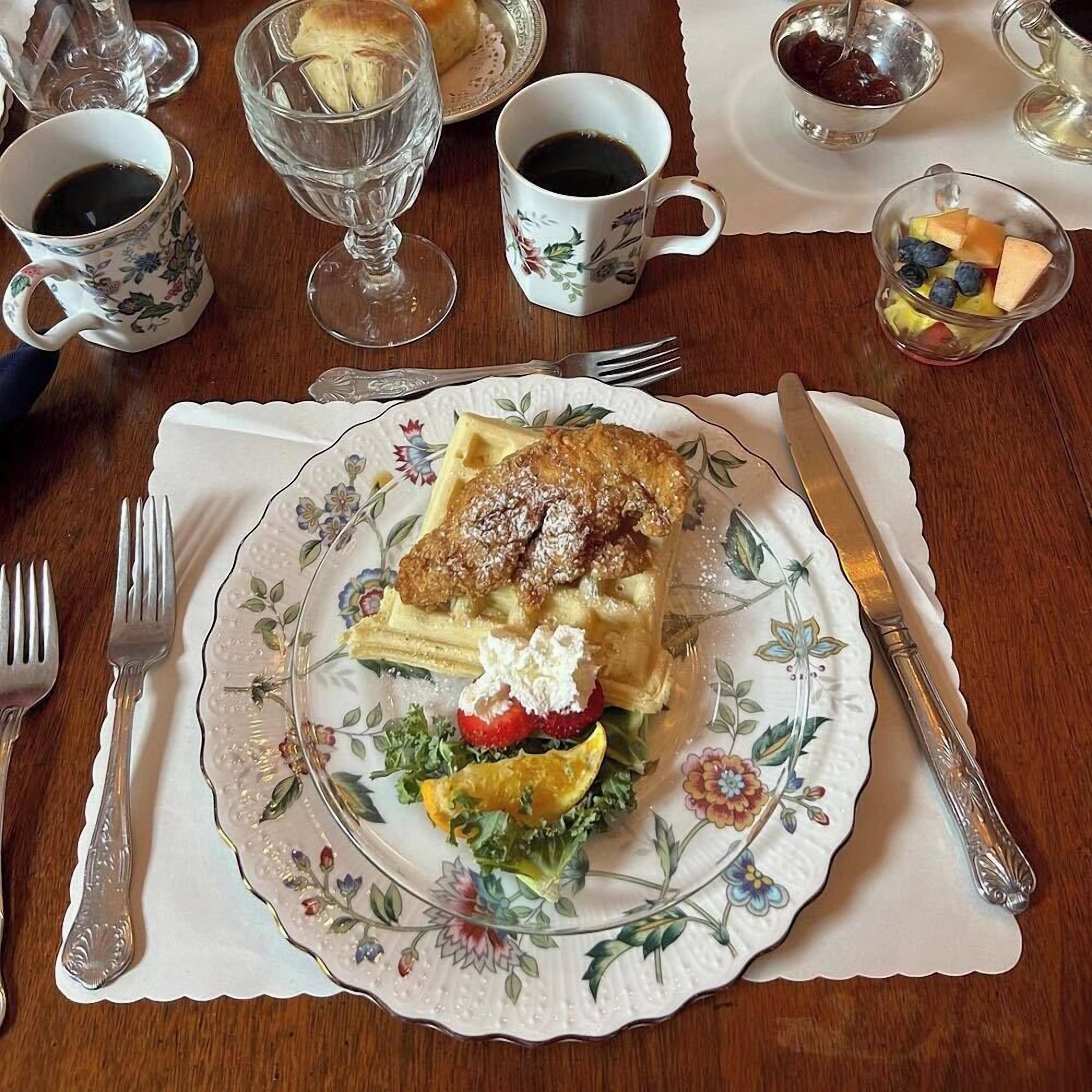 A table set with a plate of food, a cup of coffee, and a glass of water.