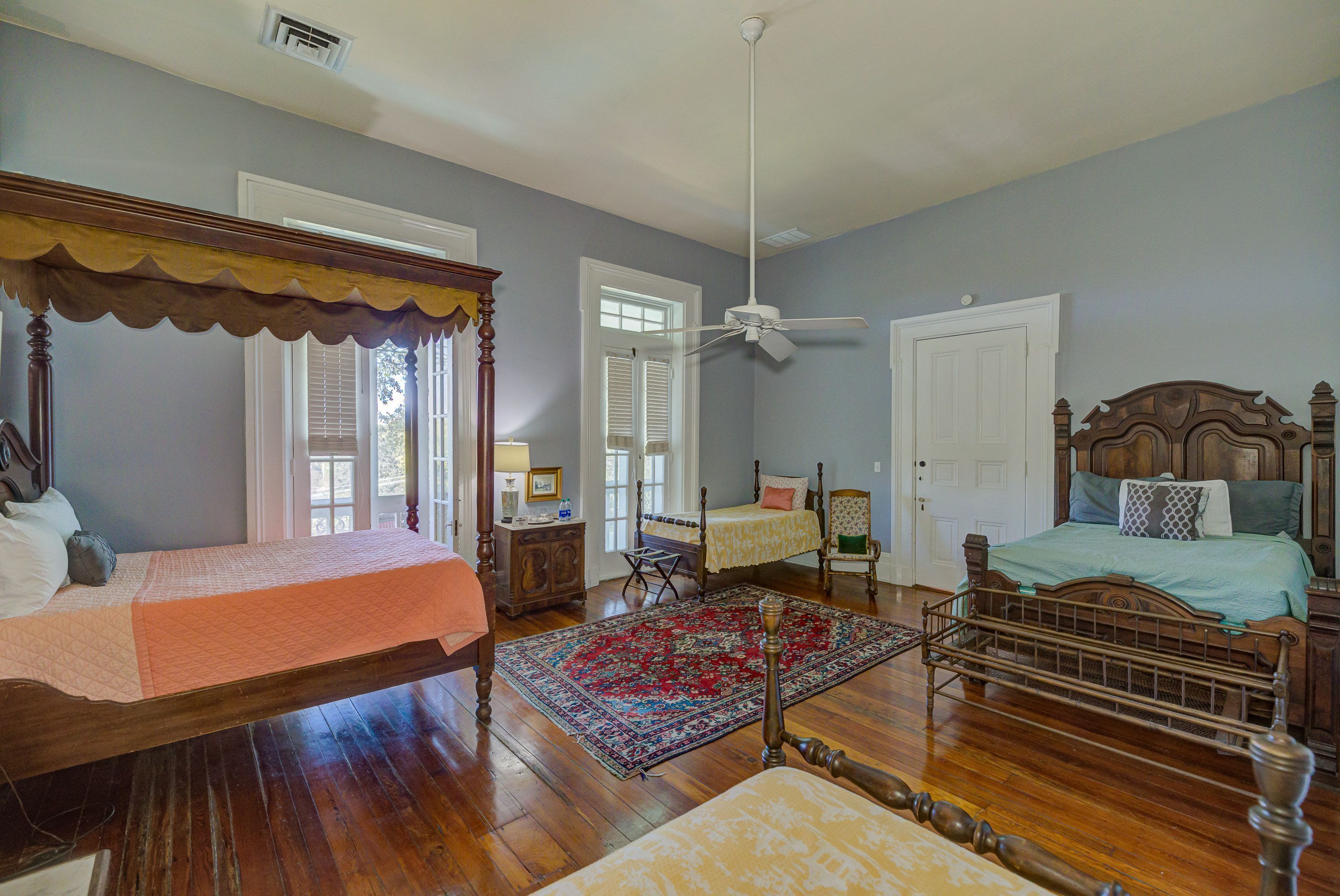A bedroom with two beds, a ceiling fan, and a large rug.