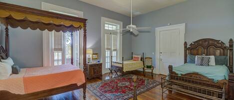A bedroom with two beds, a ceiling fan, and a large rug.