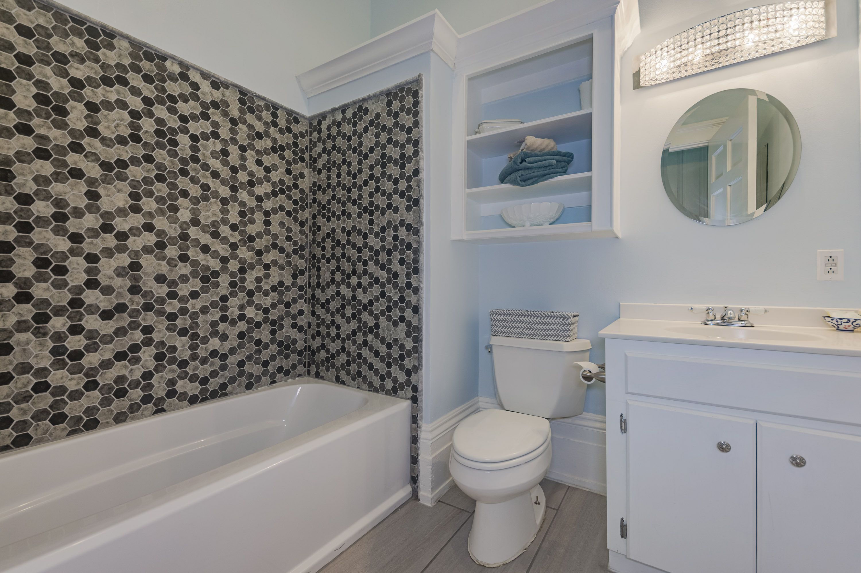 Un baño con bañera, inodoro y tocador con espejo.