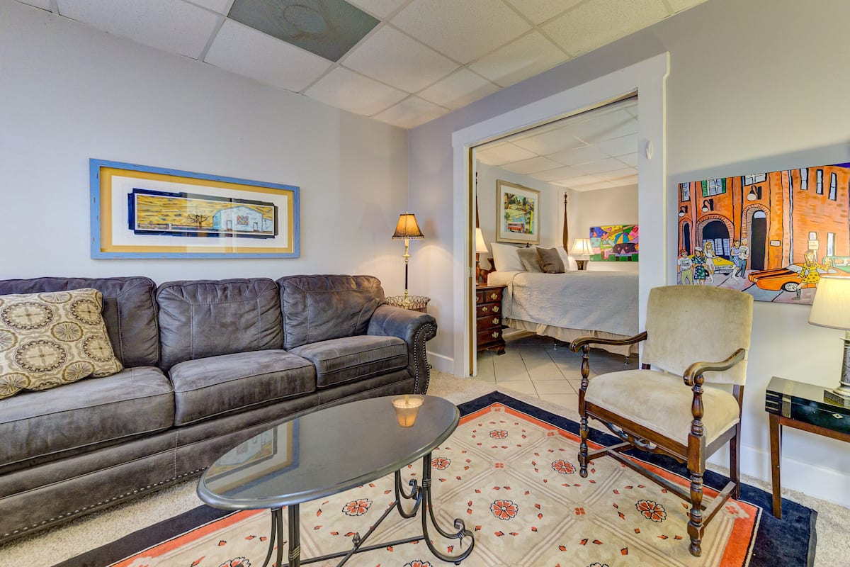 A living room with a sofa, a table, a patterned rug, and a chair.