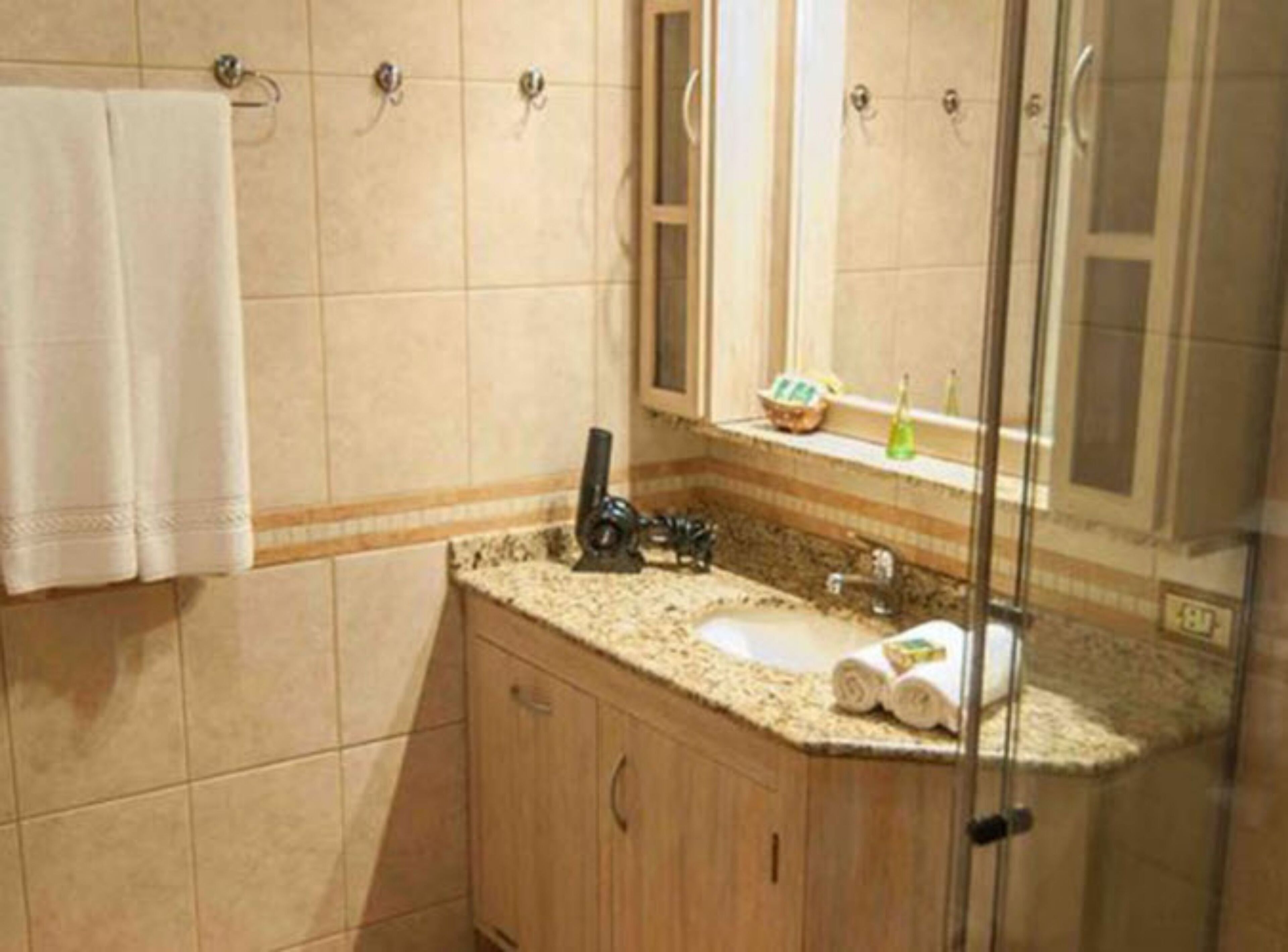 Une salle de bain équipée d’un lavabo, d’un miroir et d’un porte-serviettes.