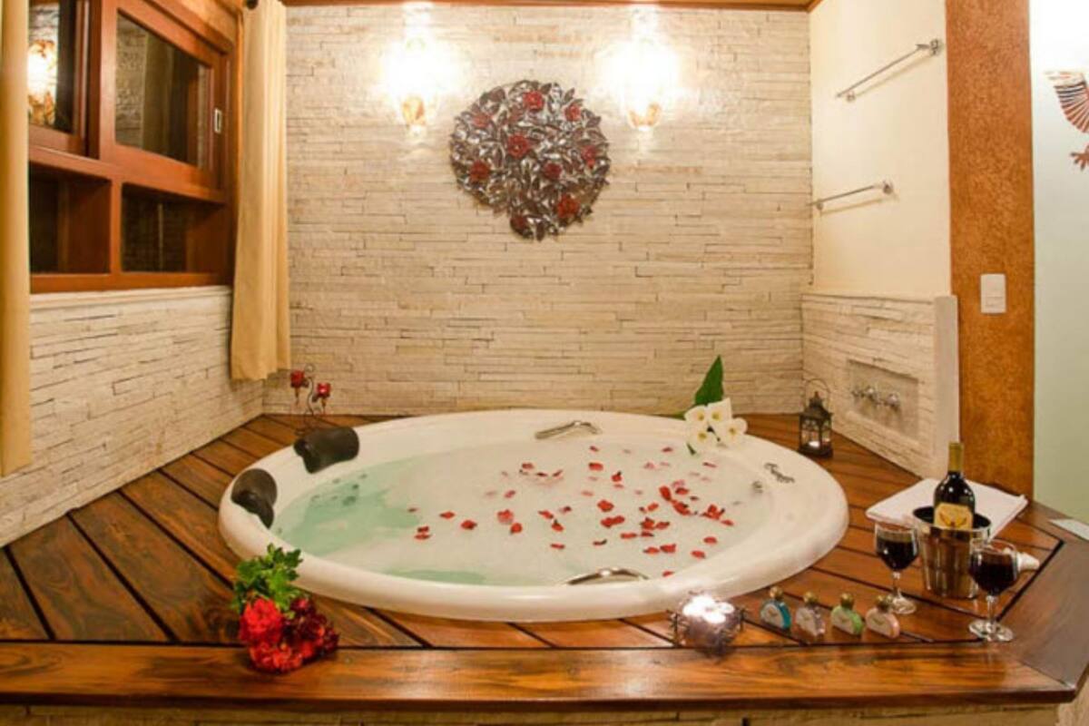 Une salle de spa dotée d’une grande baignoire, d’un plancher en bois, d’un mur en briques et d’un élément décoratif mural.