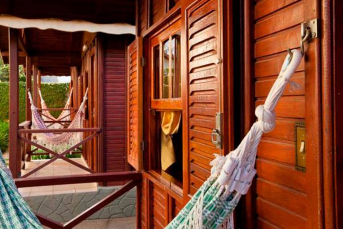 Une cabane en bois avec une véranda et un hamac.