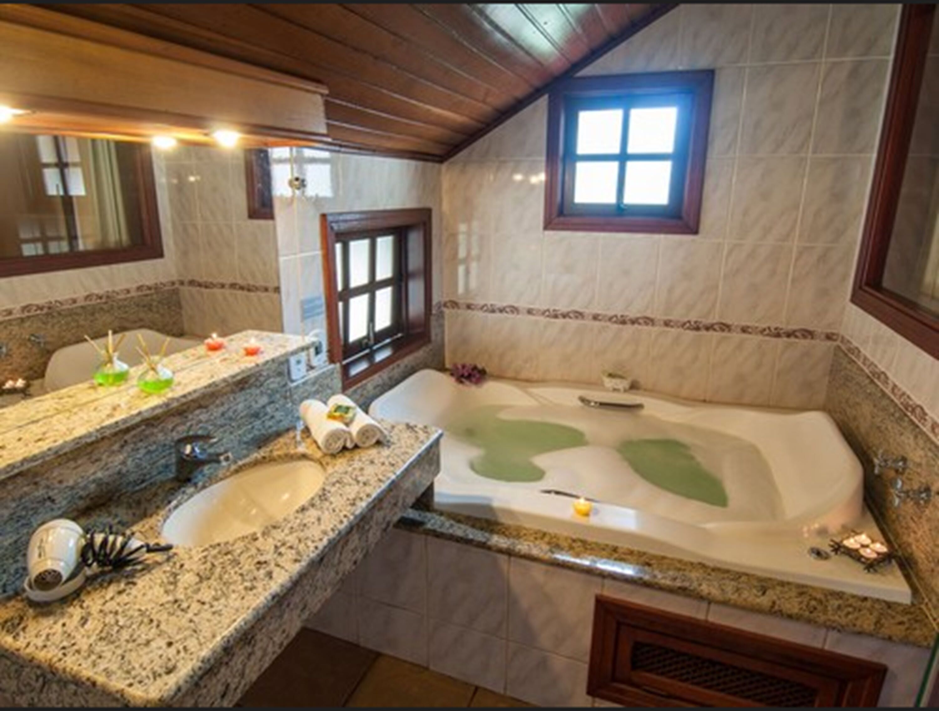 Une salle de bain dotée d’un comptoir en granit, d’une grande baignoire et d’une fenêtre offrant une vue agréable.